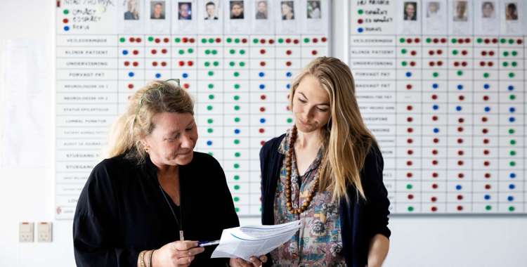 To sygeplejersker i dialog på et kontor.