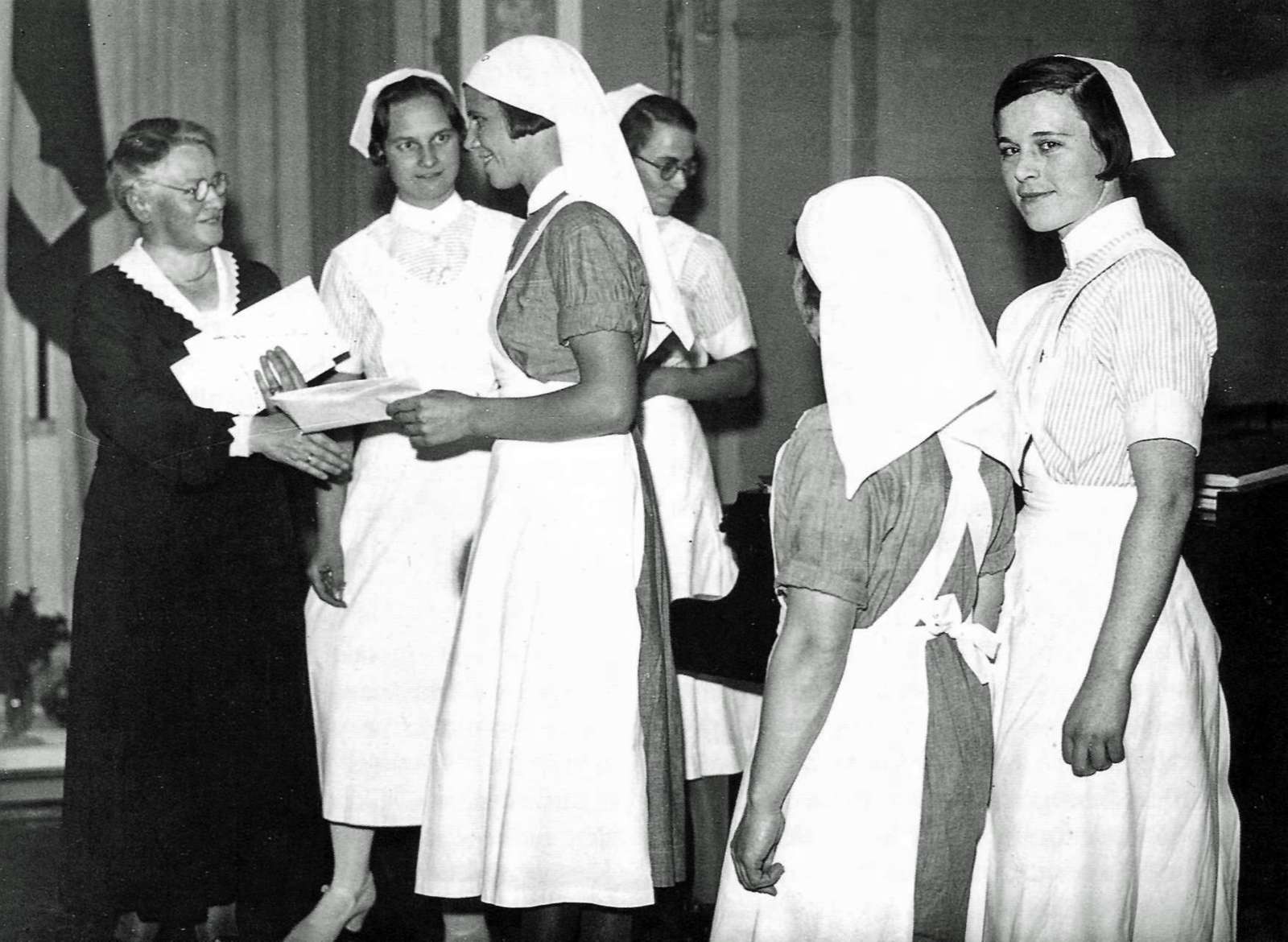 Dansk Sygeplejeråds formand, Margrethe Koch, overrækker emblem og sygeplejerskeløfte til nyuddannede sygeplejersker 1933