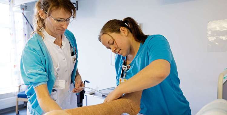 To sygeplejersker tjekker en patients ben 