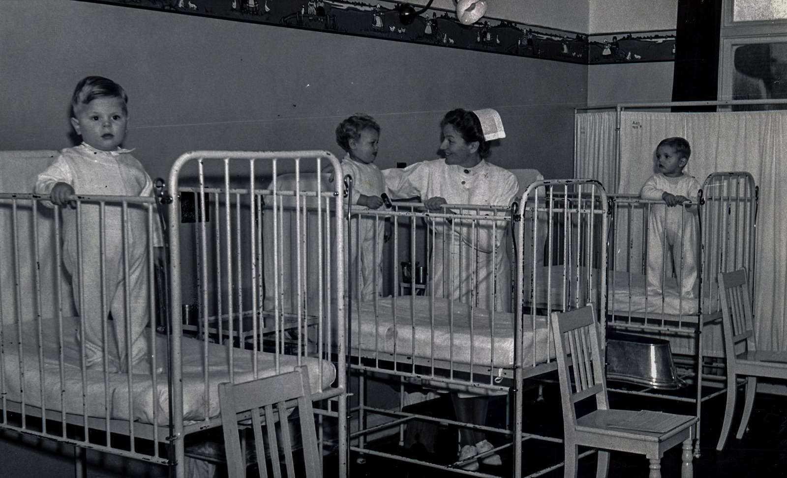 Aalborg Amtssygehus. Sygeplejerske på en børnestue med tre børn i høje senge