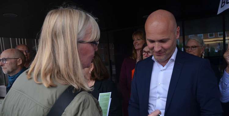 Marianne Østerlund Madsen, FTR på AUH, overrækker Regionsrådsformand Anders Kühnau en energidrik med en opfordring om at råbe Christiansborg op for flere penge til sundhedsvæsenet.