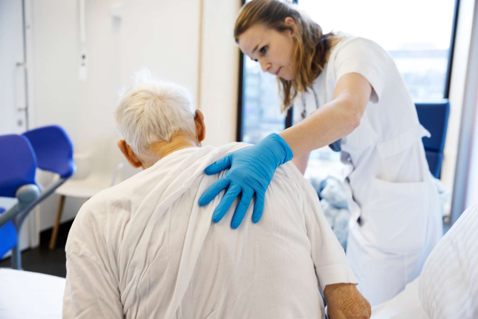 Sygeplejerske med hånd på ældre patient.