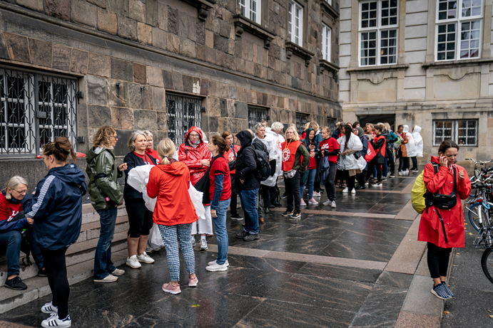 Over 100 sygeplejersker stod i kø foran Christiansborg den 26. august for at komme ind i Folketingssalen og overvære førstebehandlingen af lovindgrebet. Ind kom de, men lige meget hjalp det.