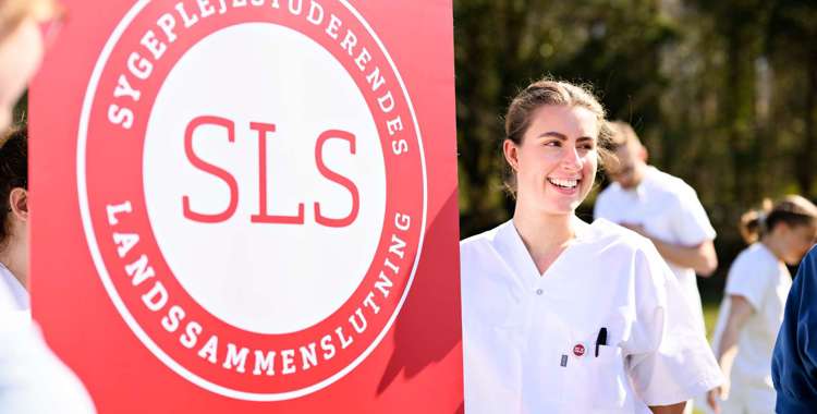 Sygeplejestuderende står med SLS-banner i solen