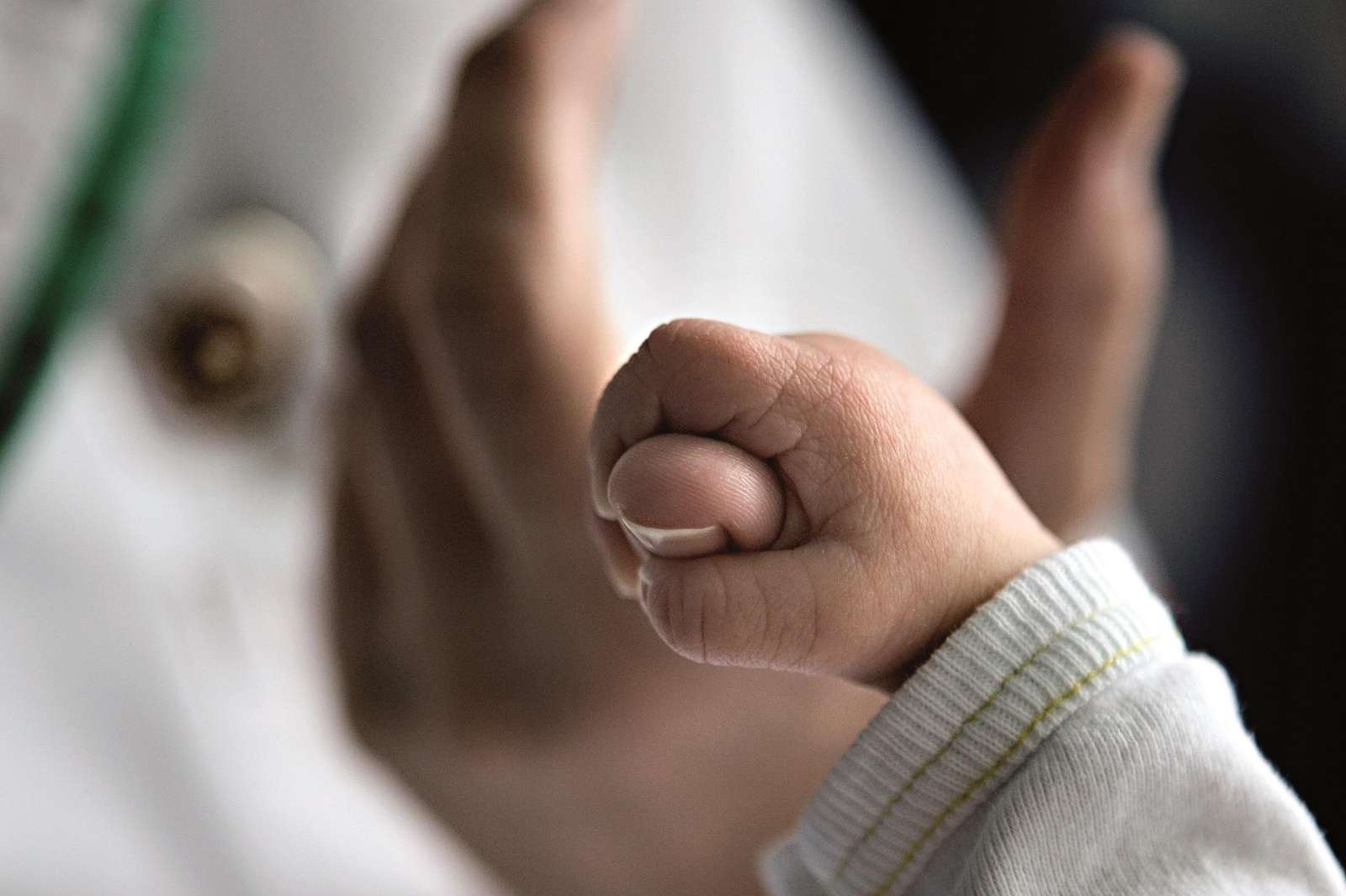 Babyhånd holder om en sygeplejerskes finger.