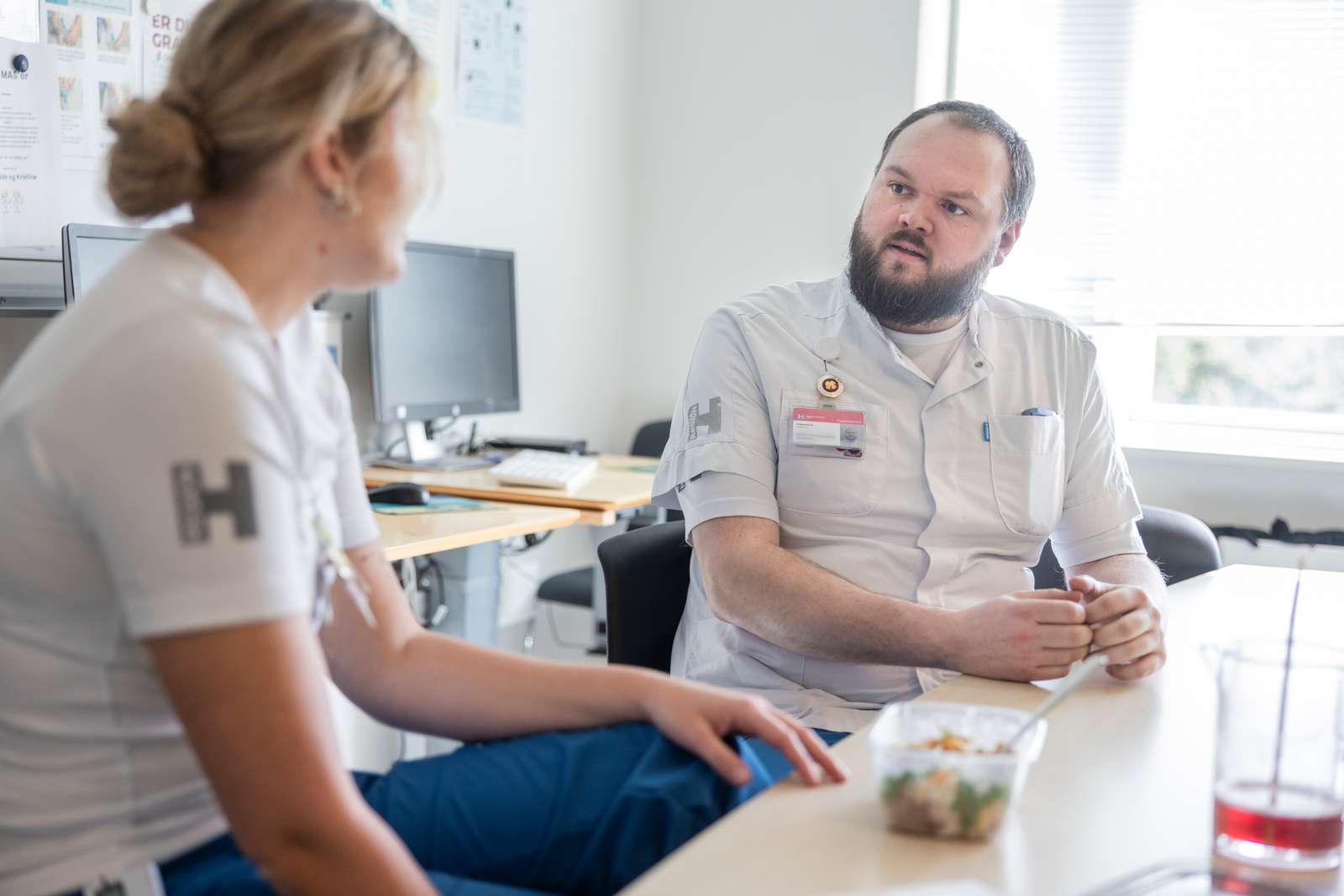 To regionalt ansatte sygeplejersker i samtale ved et bord.