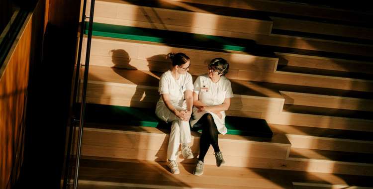 To diabetessygeplejersker sidder på en trappe og snakker