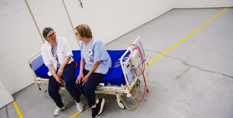 To sygeplejersker sidder i en patientseng