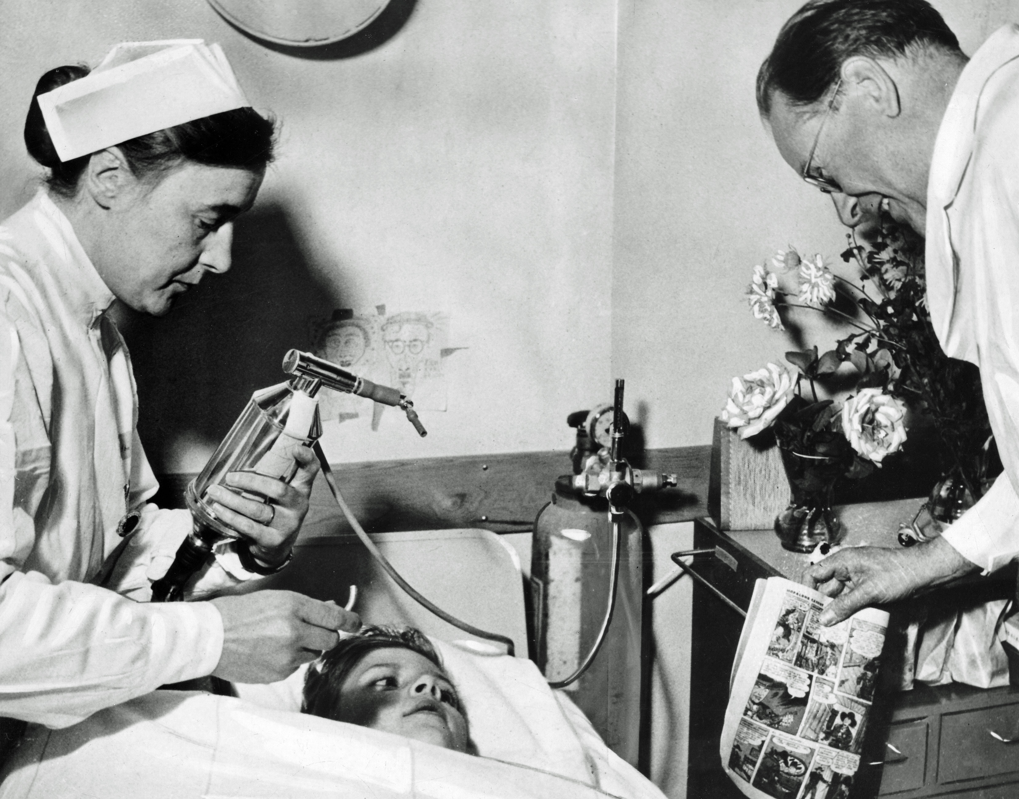 En sygeplejerske betjener håndventilationsudstyret hos en dreng med polio.