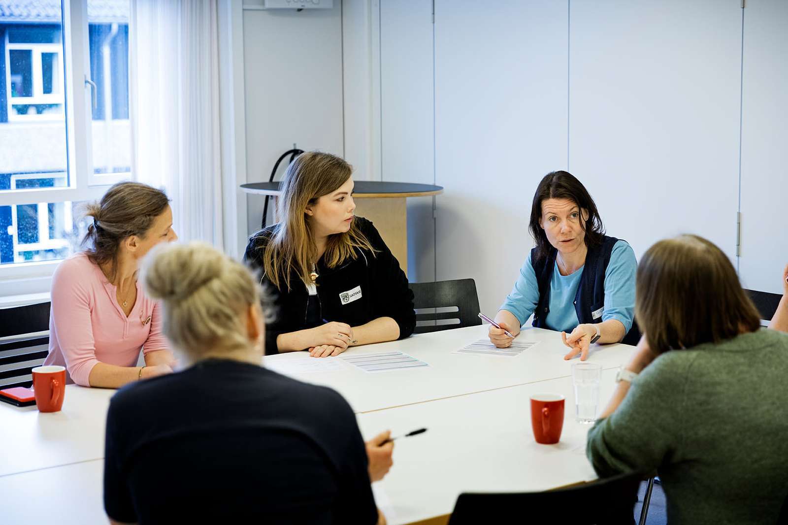 En gruppe sygeplejersker i dialog på et kontor.